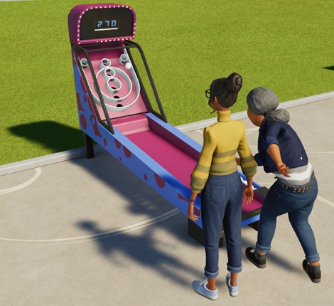 Twee Dames staan voor de 'Ballen Gooien'-machine; de rechtse heeft net een bal naar achteren doen rollen. De speelkast is blauw en paars ingekleurd. Bovenaan staat een digitale scoreteller.