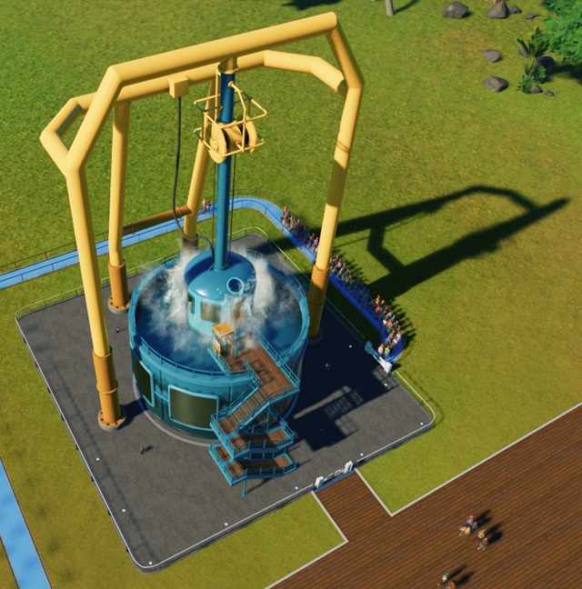 Vogelperspectief van een Buoyancy-attractie. Deze bestaat uit een verticale, blauwe cilindervormige watertank met een geel frame erboven. Aan een enorme katrol hangt de 'duikersklok' met de Bezoekers. Deze 'duikersklok' wordt op en neer bewogen, in en uit de watertank. Op de foto plonst de 'duikersklok' in het water. Vele Bezoekers wachten rechts hun beurt af. Aan de watertank hangen zigzag-trappen vast; de bedieningspost zit bovenaan de trap.