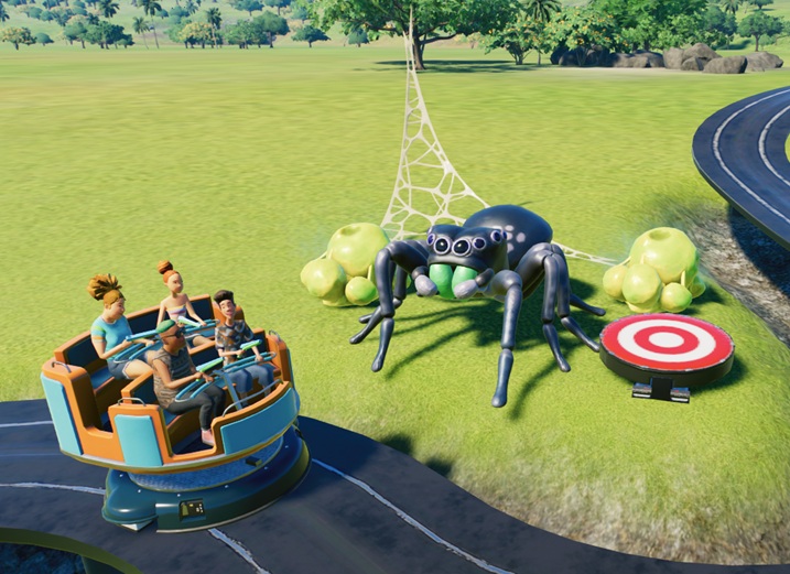 Een karretje, gevuld met vier Bezoekers, rijdt links langs een animatronische spin met spinneweb en twee eierzakken. Rechts staat een rood/wit doelwit, dat net werd neergeschoten.