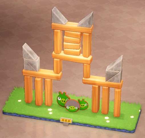 Een 'Fort' opgebouwd uit houten en stenen bouwblokken, met de stenen blokken als 'kantelen'. Onderin het 'Fort' zitten drie 'Bad Piggies'.