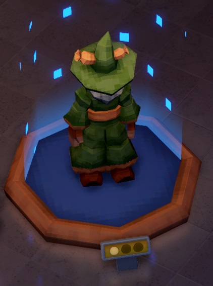 Een afbeelding van de hoofdfiguur uit de Meat Wizard-videospellen, opgebouwd uit pixels, met vele kleine, vierkantige, blauwe partikels die rond het Museumstuk zweven. Het is een driedimensionaal object: een tovenaar met groene punthoed en groen kleed. Door de hoed steekt een worst. De hoed verbergt het gezicht van de tovenaar grotendeels - enkel de onderkant van zijn grijze baard is zichtbaar.